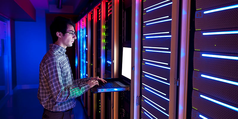man working with a keyboard and monitor in a data center