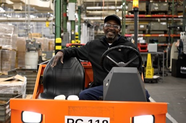 An S&C team member smiles while operating a machine handling truck