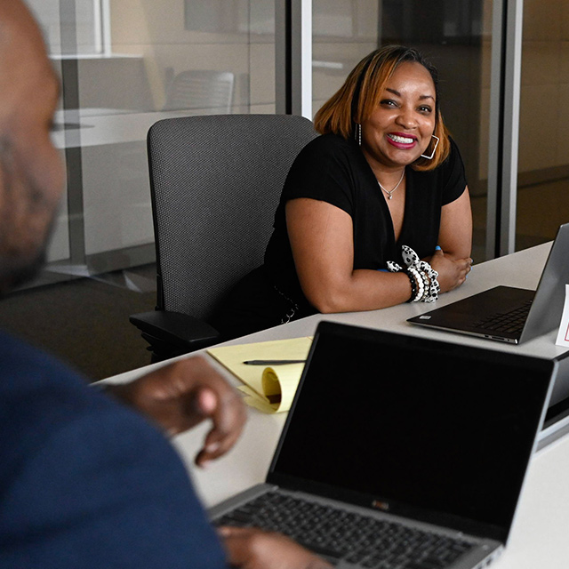 Two team members meet in a conference room to collaborate on a project. collaboration, teamwork, meeting, conference room, diversity, DEI, DE&I, team, careers, jobs